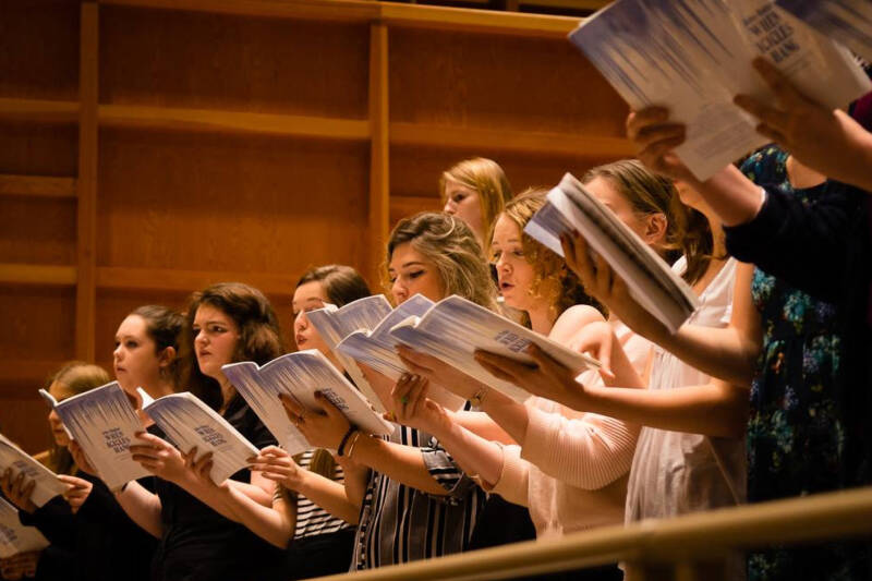 Choir members holding the choral scores and singing